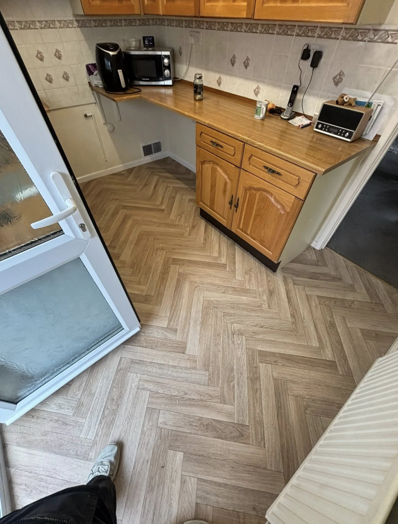 Herringbone-pattern wood-effect flooring fitted in a bright kitchen